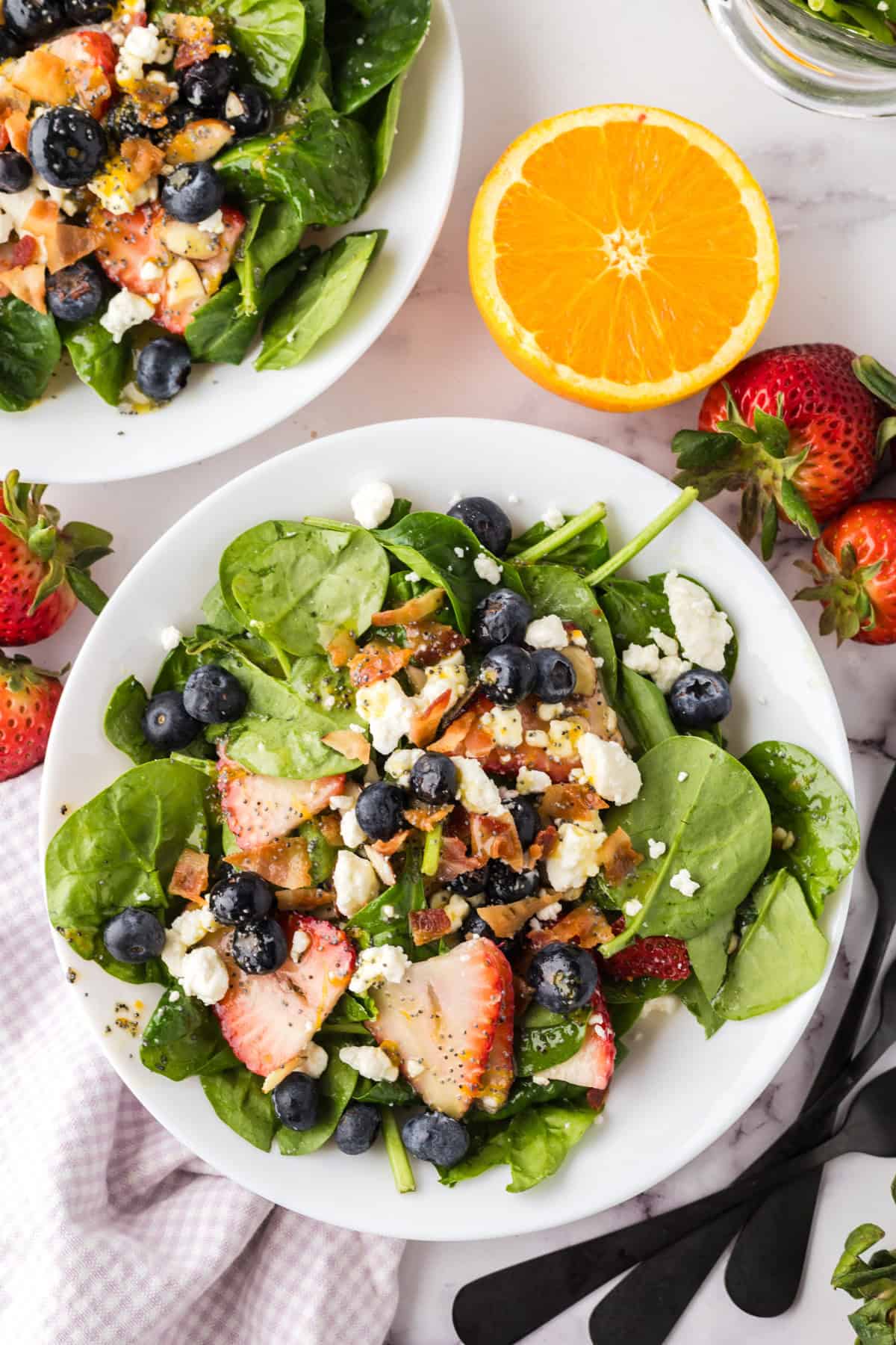 spinach and berry salad on a round white plate.
