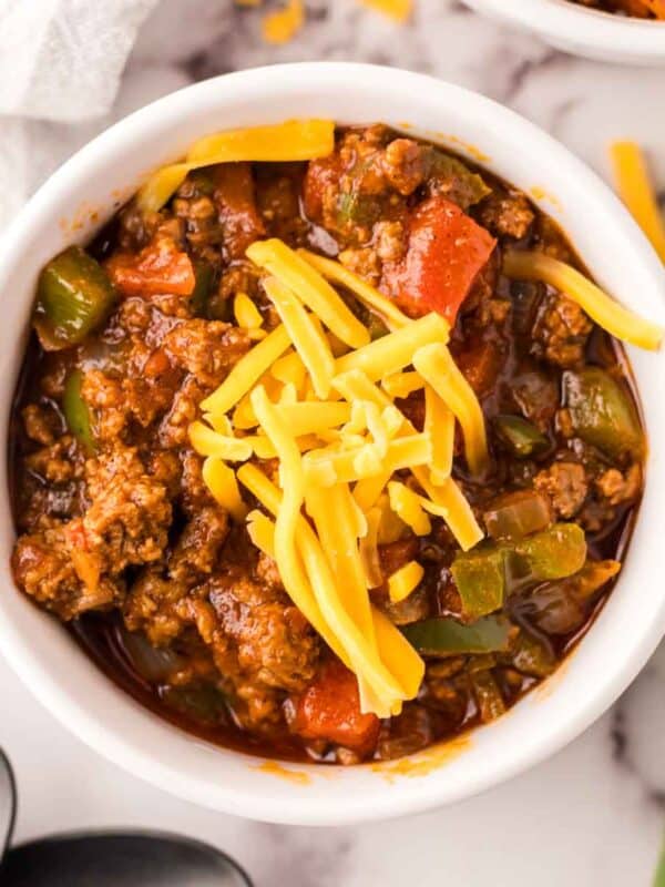 small bowl of texas chili with shredded cheese on top and jalapeños around.