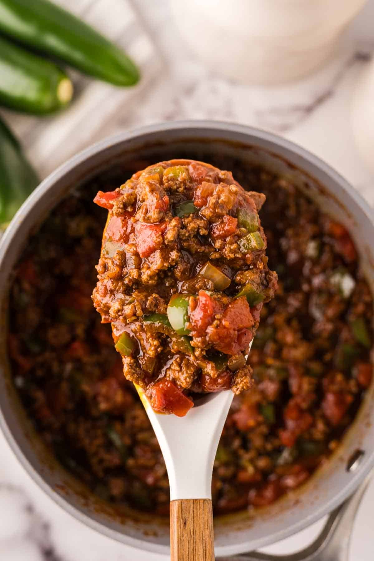 spoonful of texas chili over the pot ready to serve.