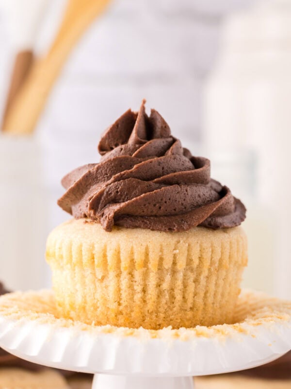 vanilla cupcakes with chocolate frosting on an ornate stand.