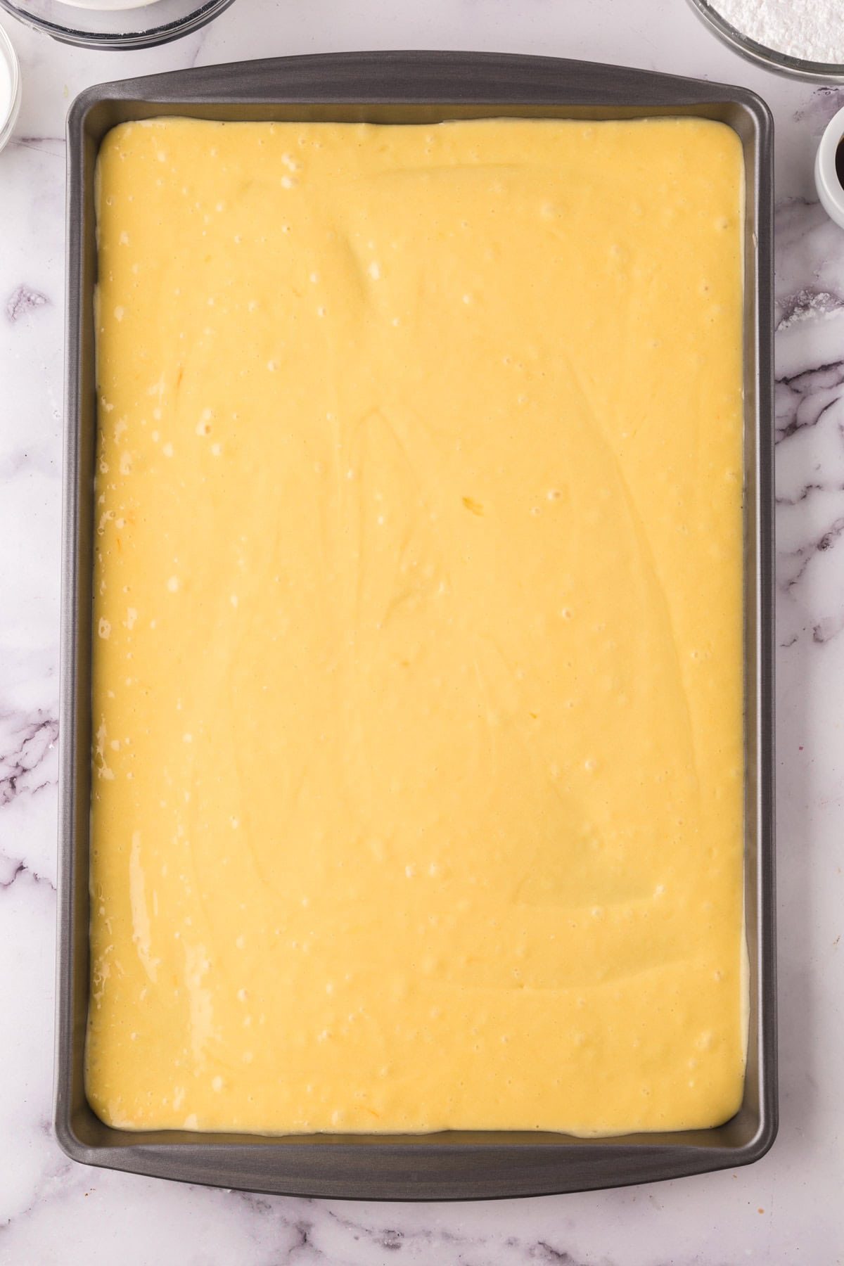 sheet pan with vanilla cake batter raw ready for the oven.