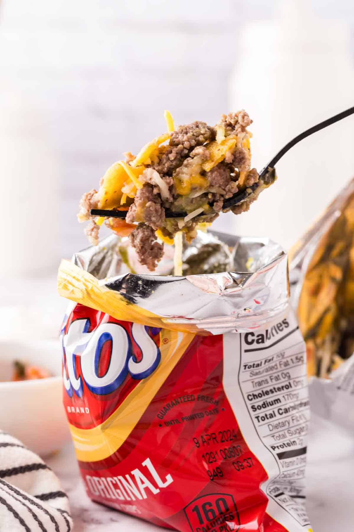 Fritos small chip bag with walking taco recipe inside with a fork full.