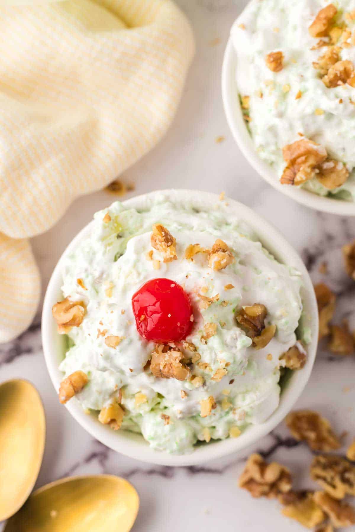 small dish with watergate salad recipe with nuts and a cherry on top.