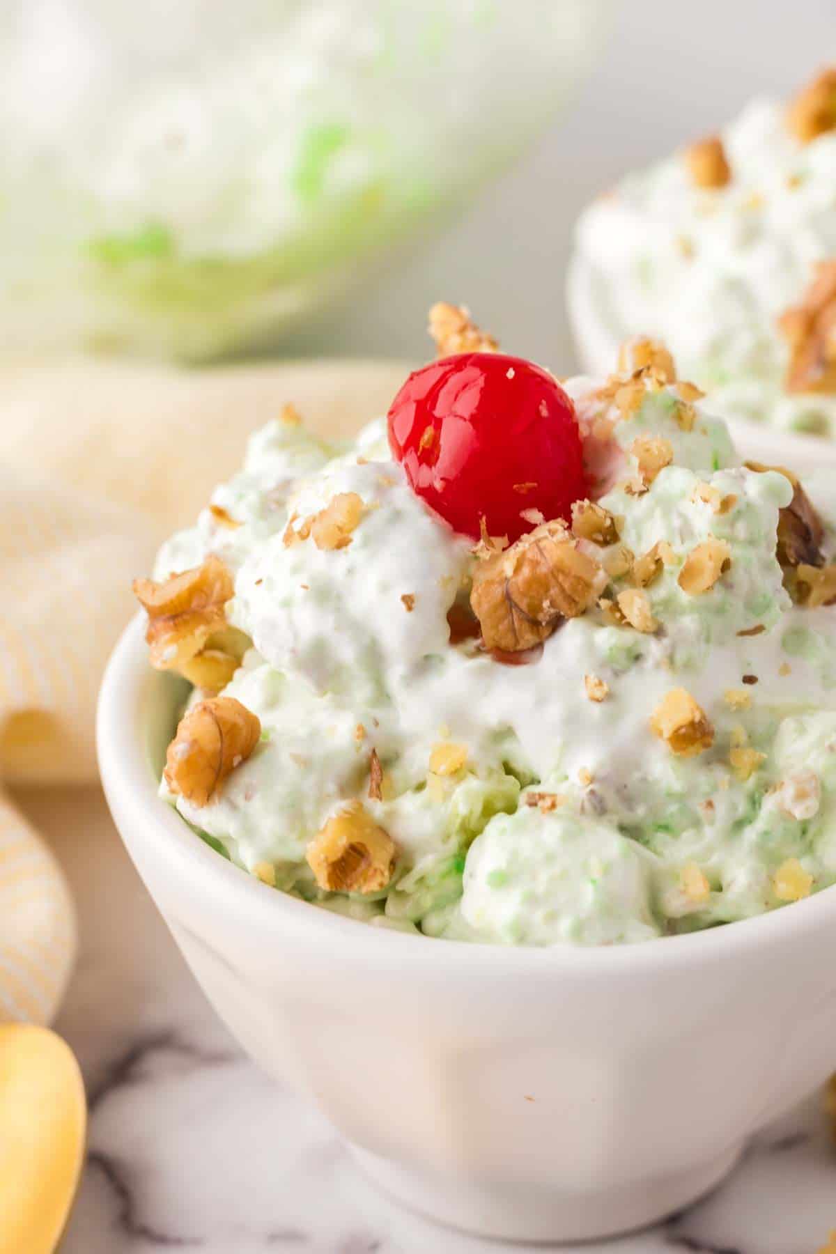 small dish with watergate salad recipe with nuts and a cherry on top.