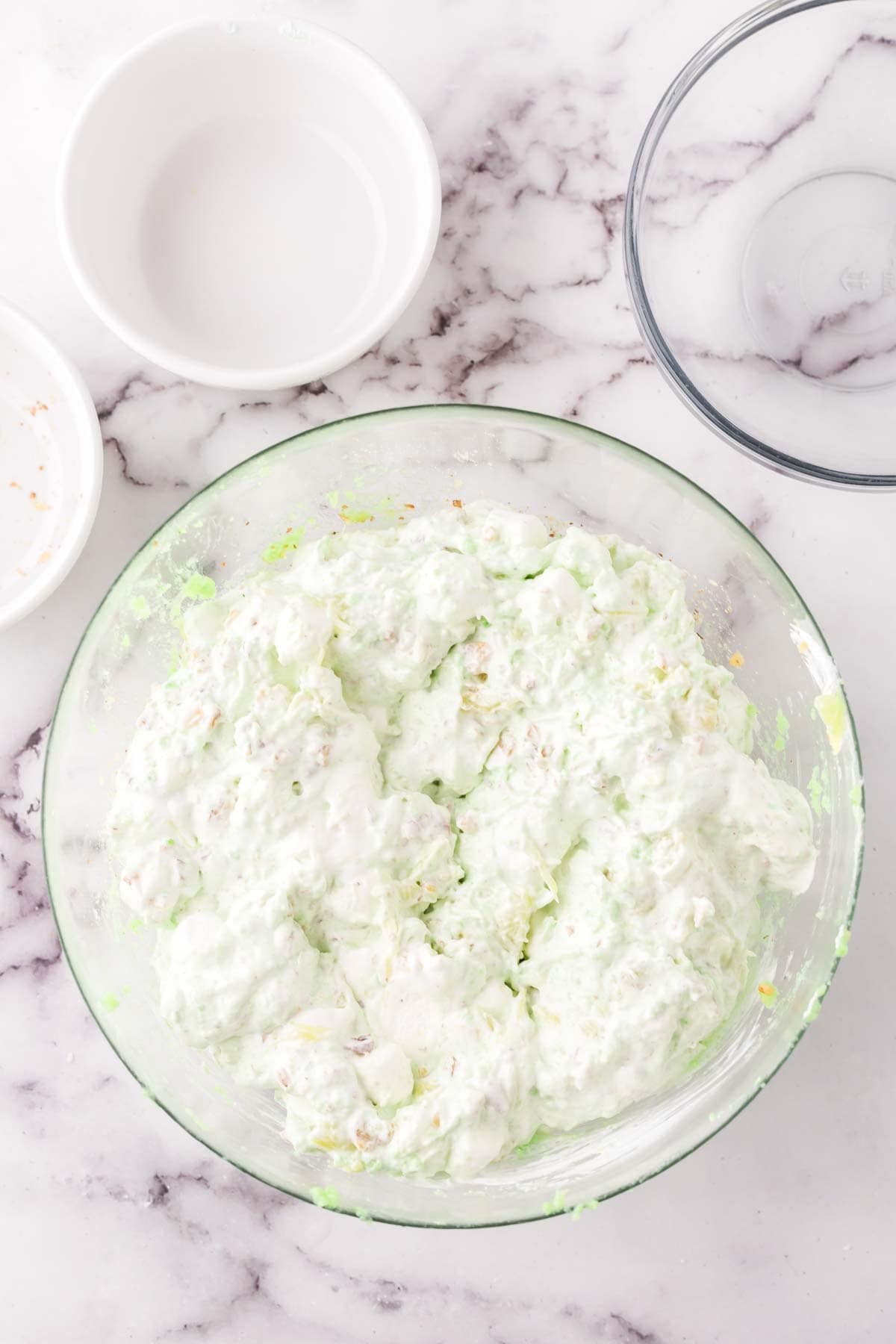 clear mixing bowl in the process of making watergate salad.