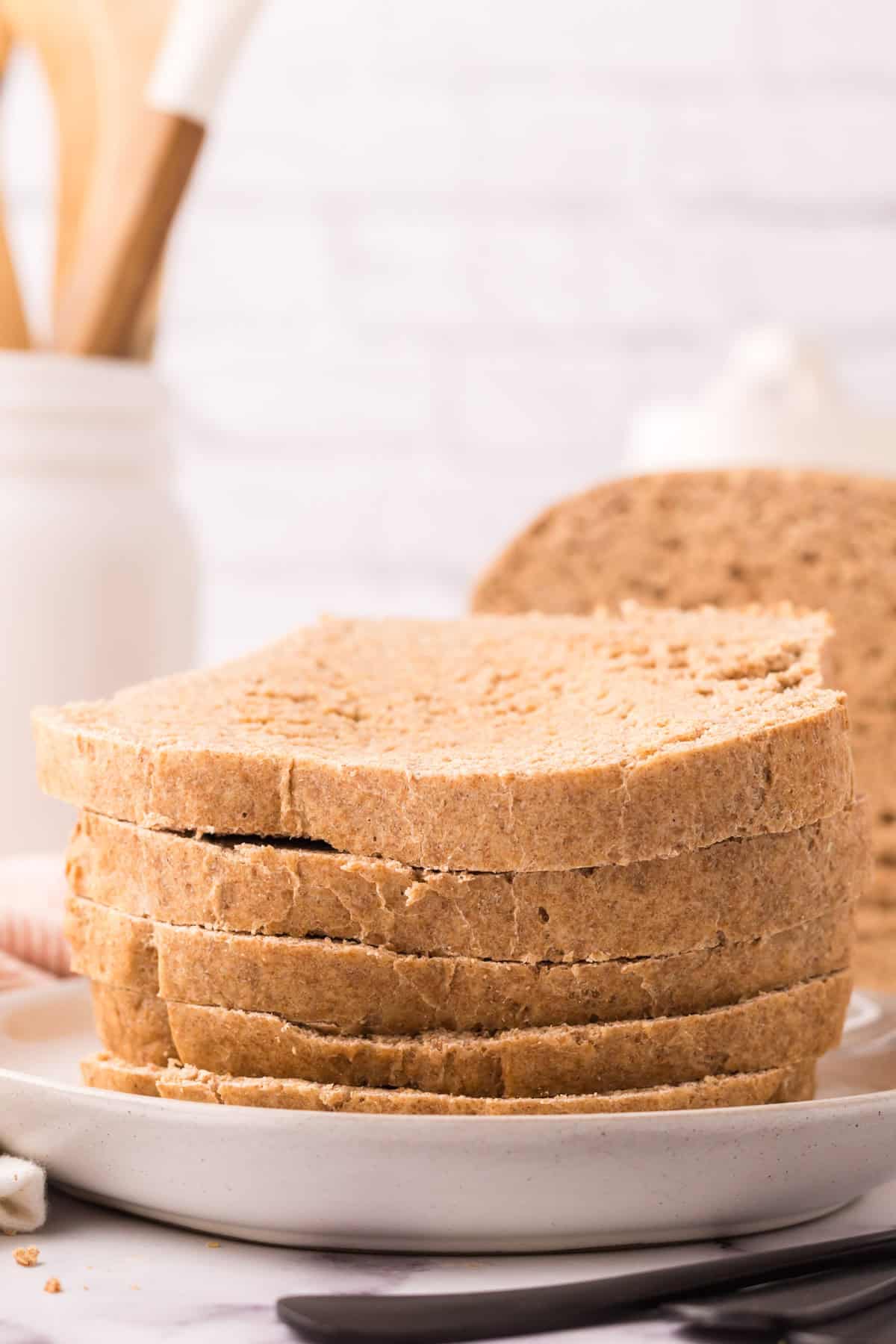 whole wheat sandwich bread recipe slices stacked on a white plate.