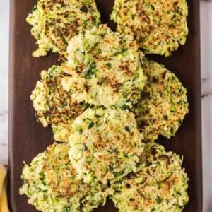 wooden board with a pile of zucchini fritters.