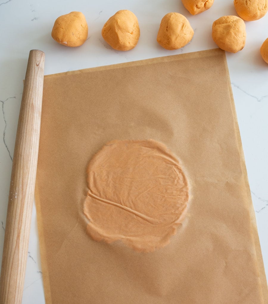 Cassava flour and sweet potato tortilla dough rolled between two sheets of parchment paper.