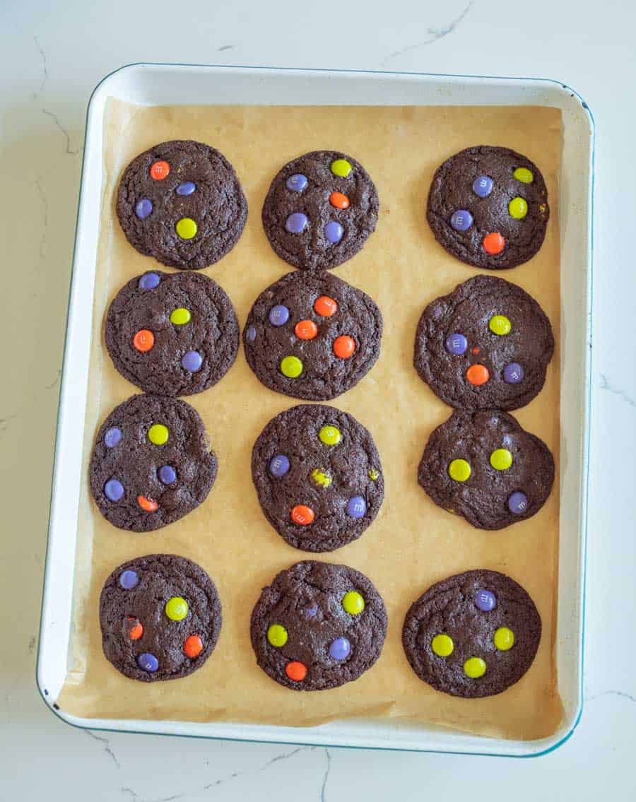Cookie sheet with 12 dark chocolate cookies with Halloween M&Ms baked in.