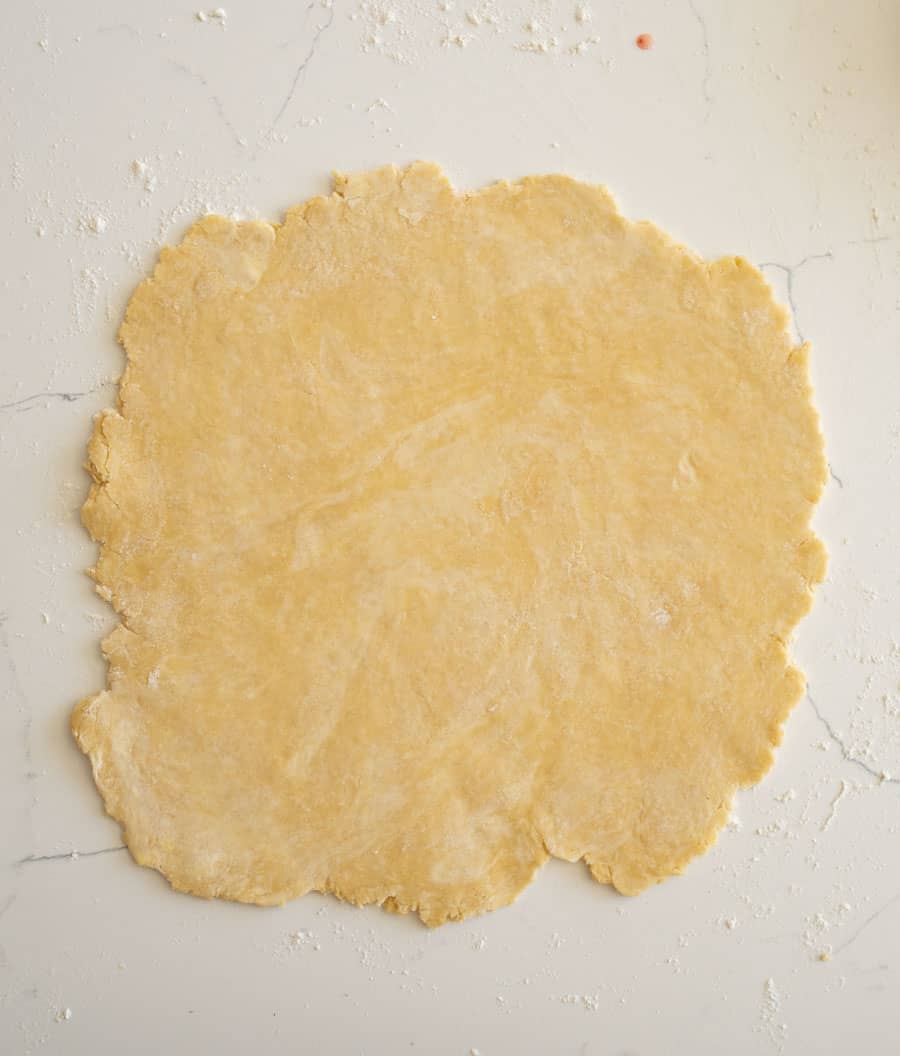 An evenly rolled out pie crust on a white counter. 