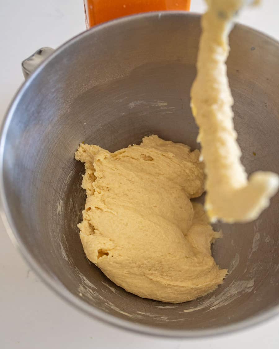 Image of the dough in a mixing bowl being mixed with a dough hook. 