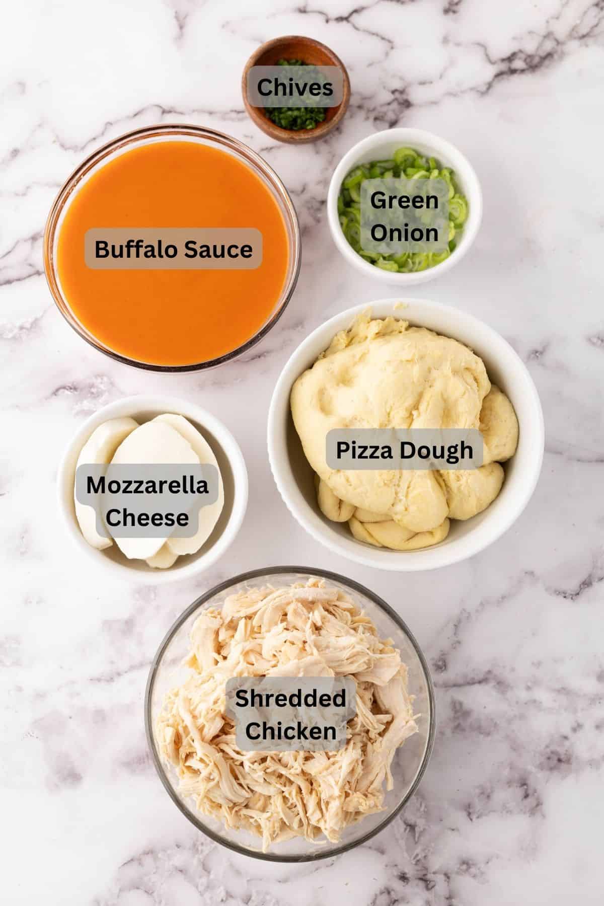 portion bowls each with digitally labeled raw ingredients to make buffalo chicken pizza.