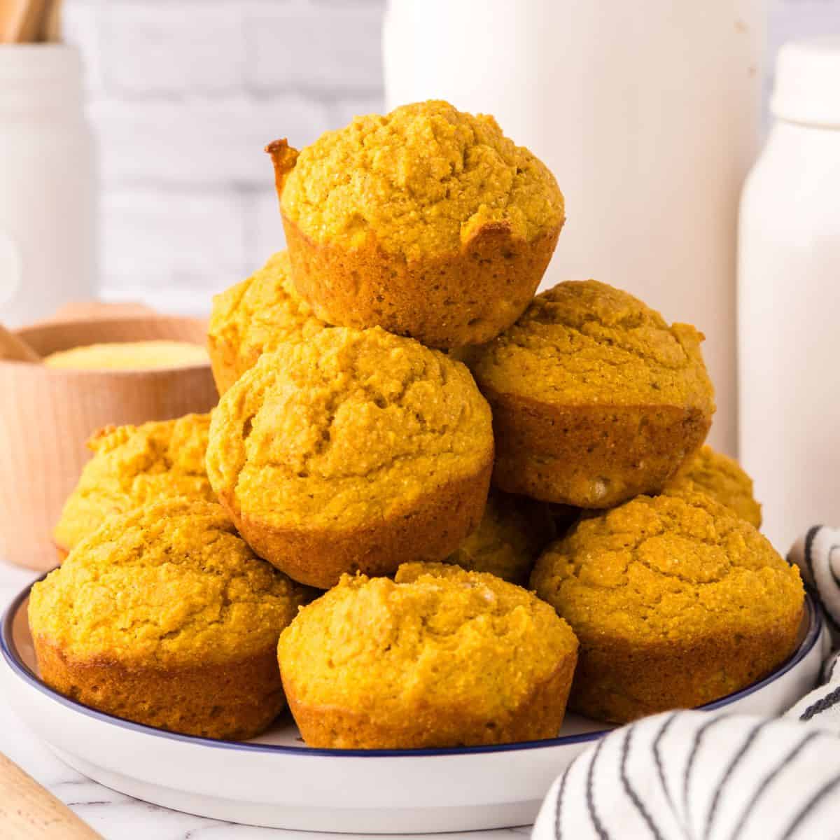 big stack of pumpkin cornbread muffins on a plate.