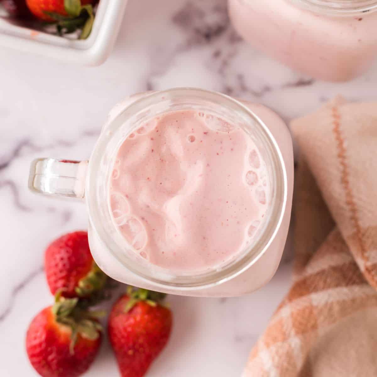 strawberry milkshake in a glass mason jar.