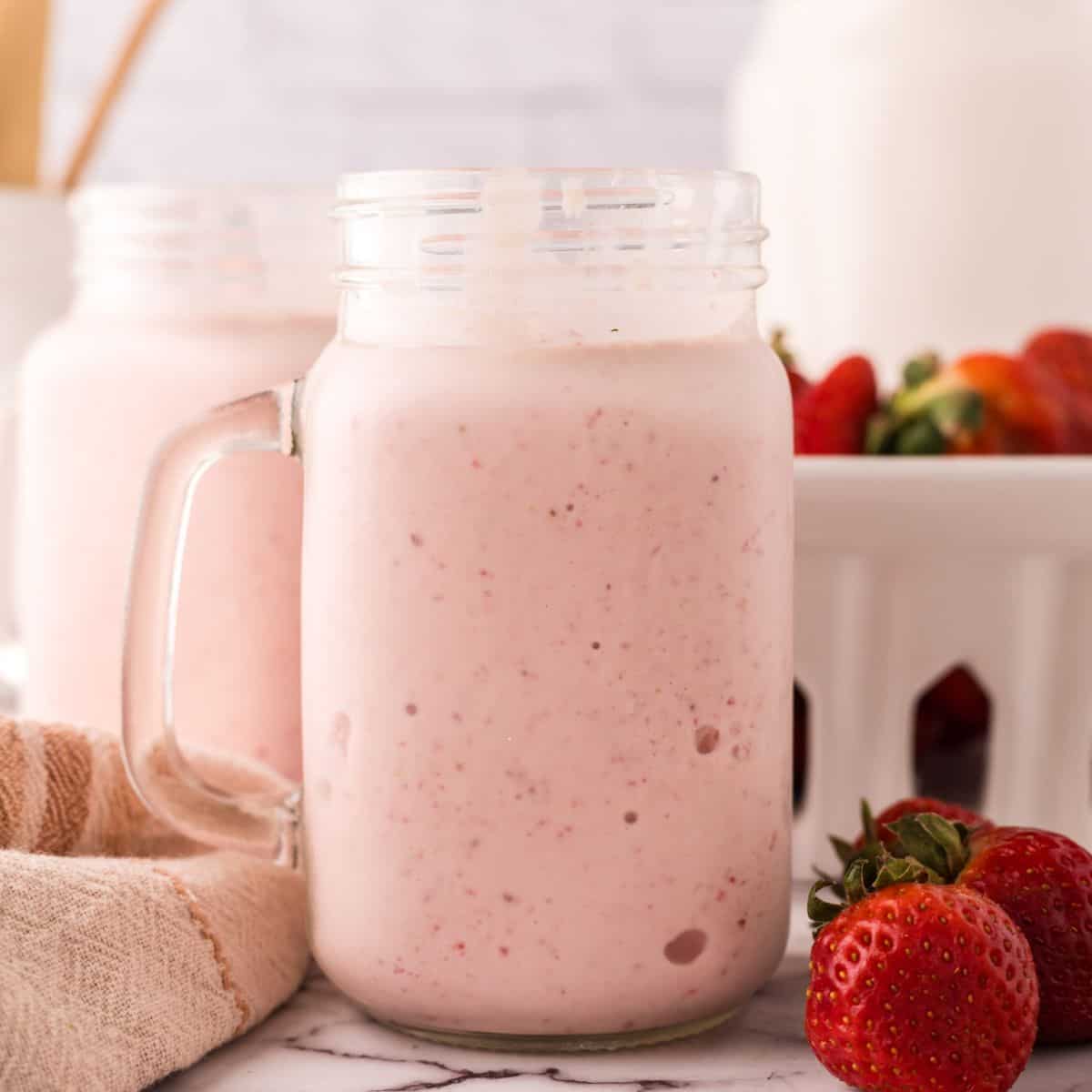 strawberry milkshake in a glass mason jar.