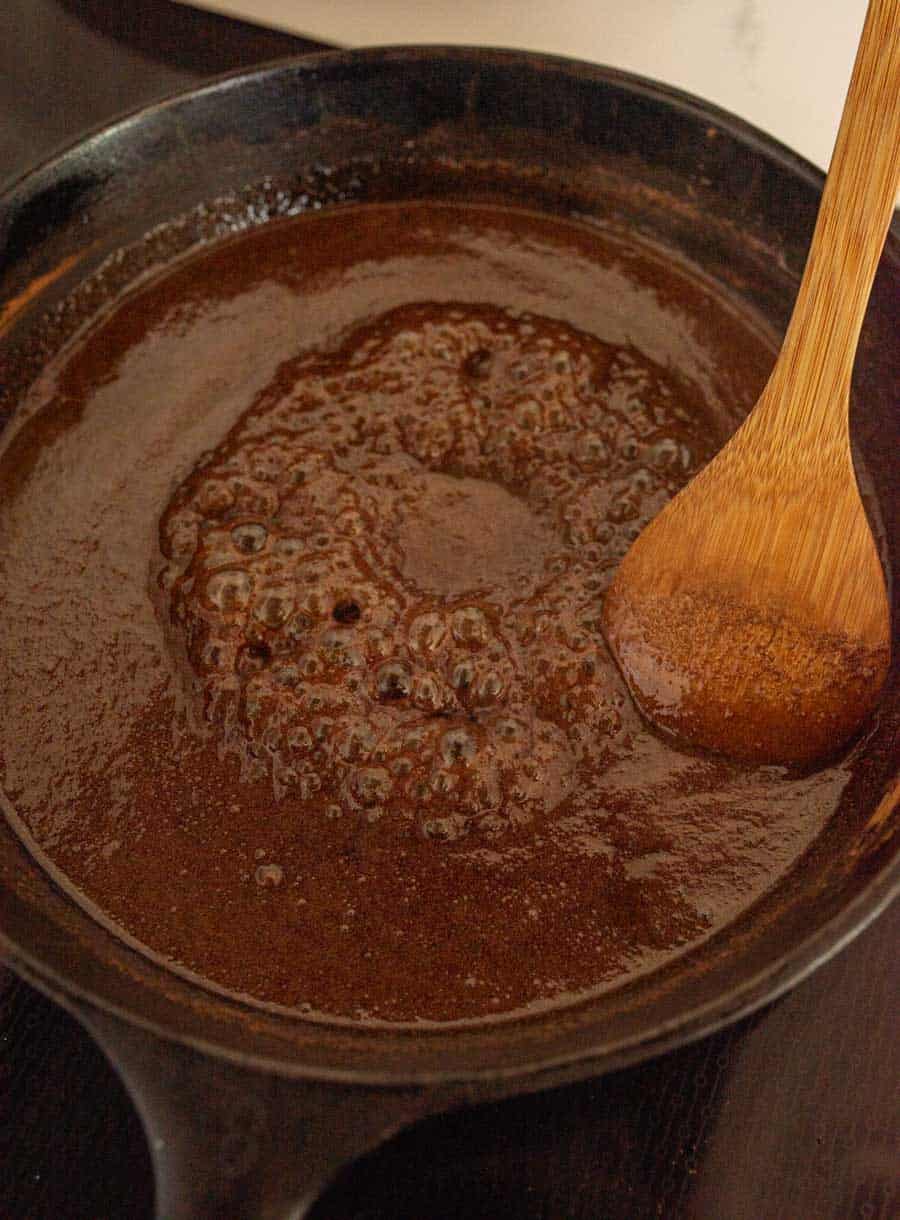 The sugary sauce bubbling in a cast iron pan. 