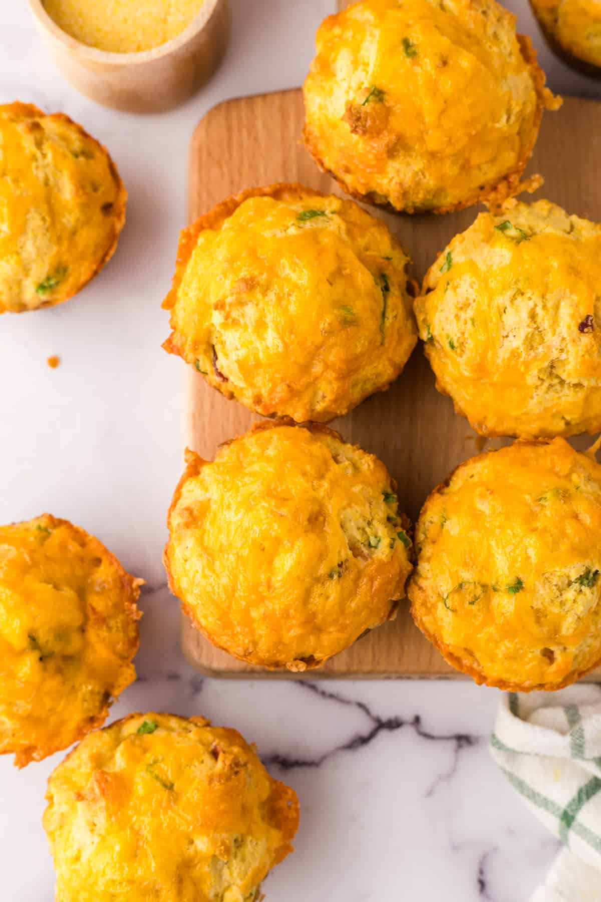 baked cheddar bacon cornbread muffins on a wooden board.