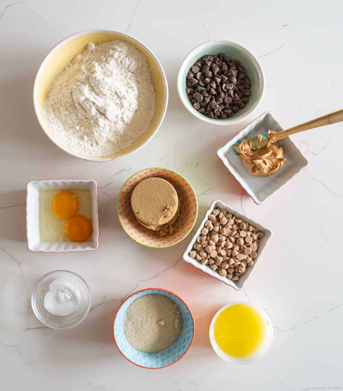 portion bowls each with raw ingredients to make chocolate chip cookies with peanut butter chips recipe.