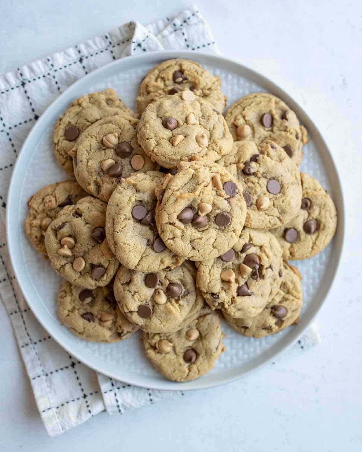 chocolate chip cookies with peanut butter chips in a pile on a round plate.