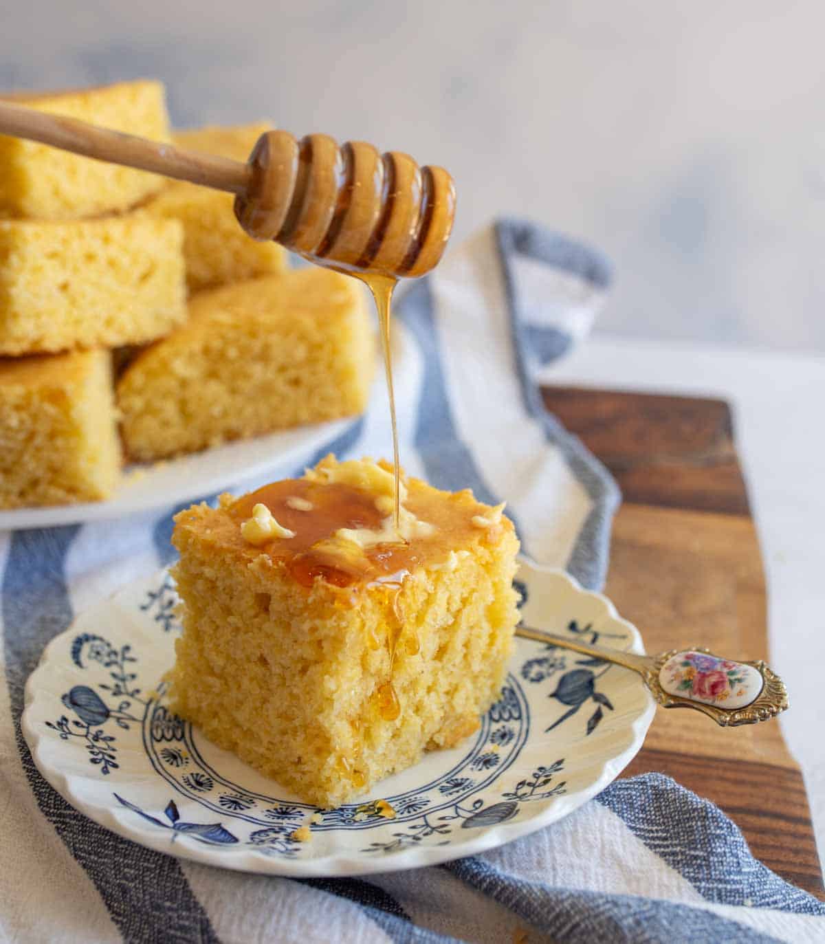 cornbread with butter and honey on a plate.