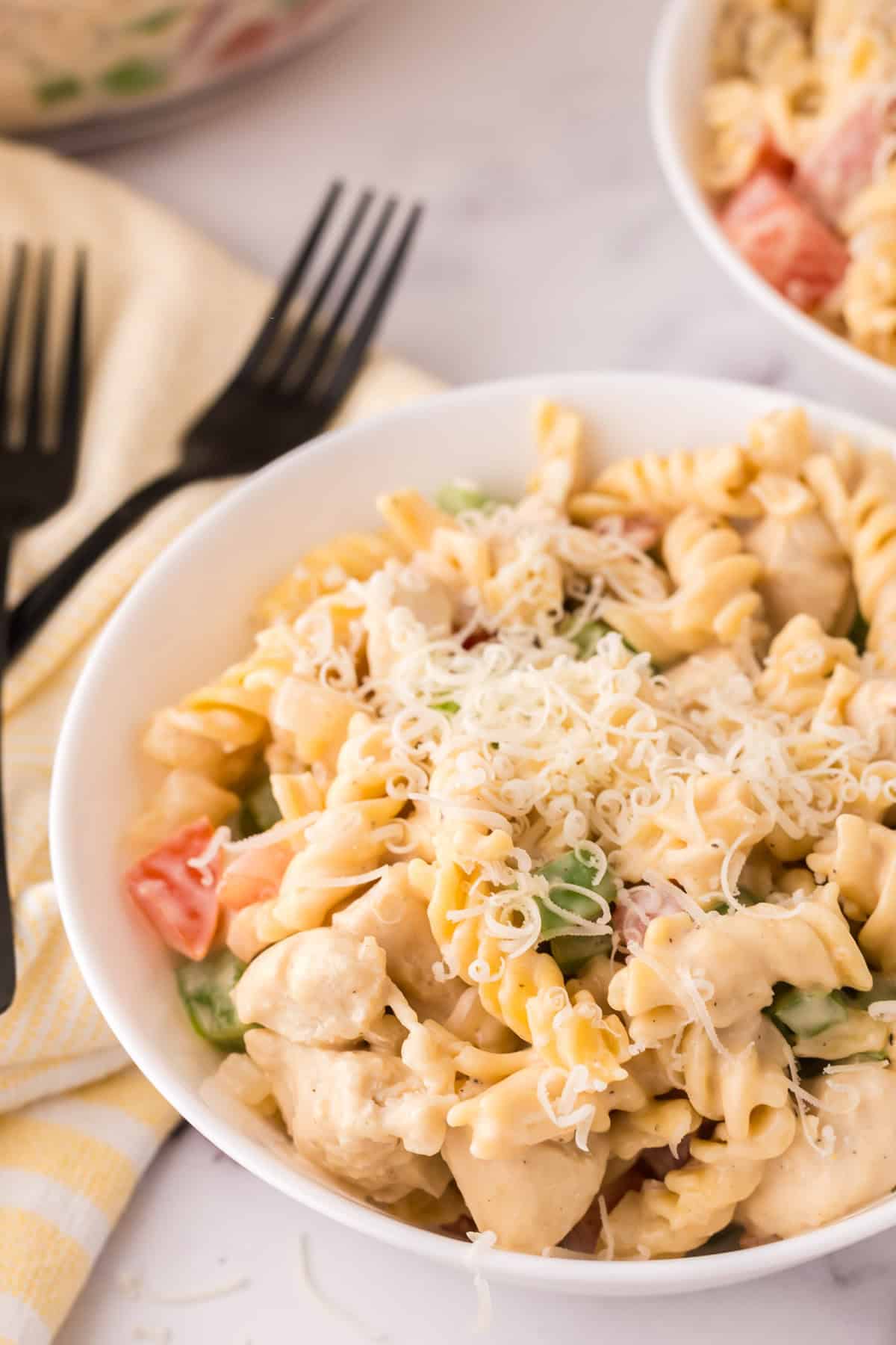 Creamy chicken bacon pasta in a white bowl with a black fork.