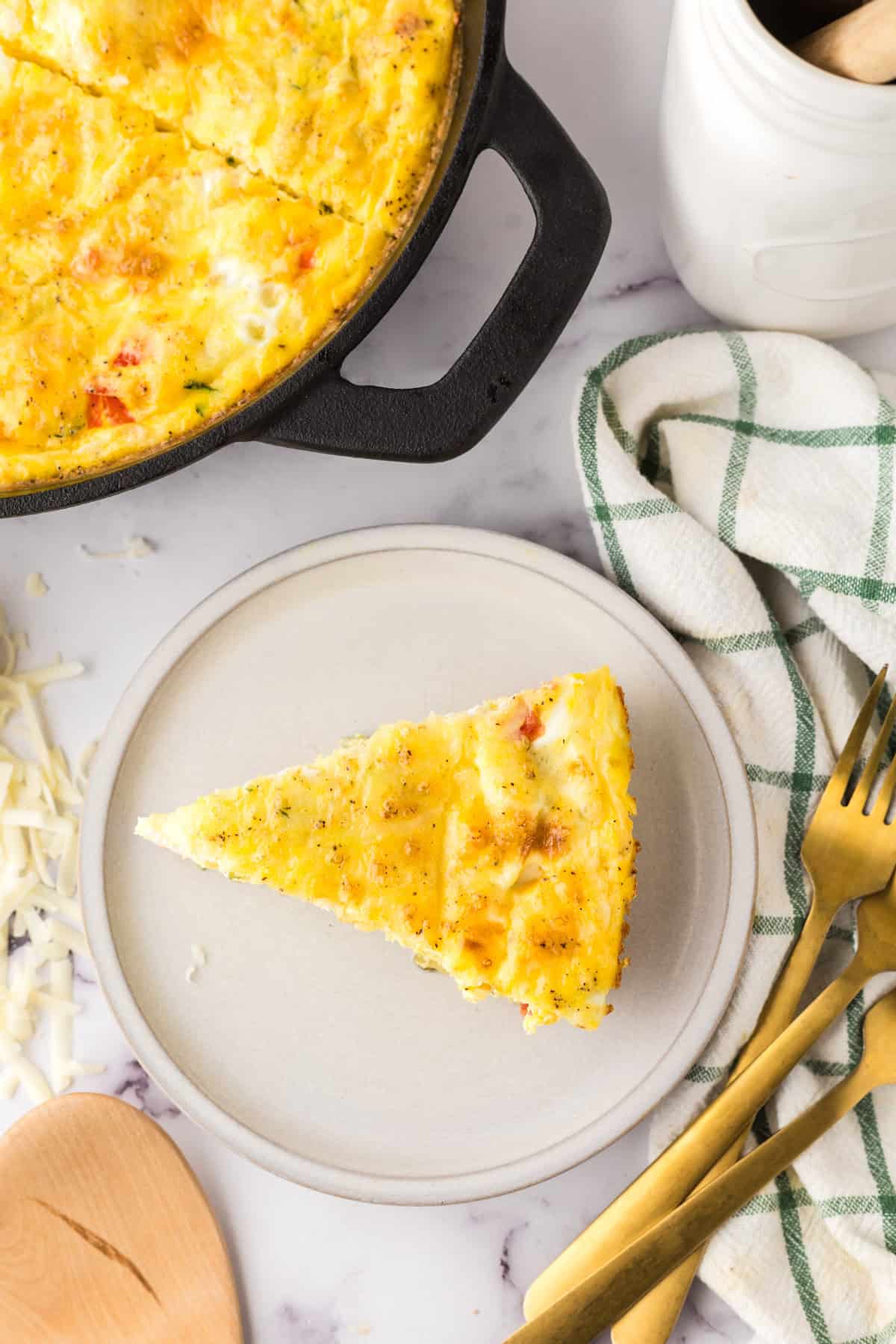 Farmhouse egg bake recipe in a triangle pie slice on a round plate with golden forks.