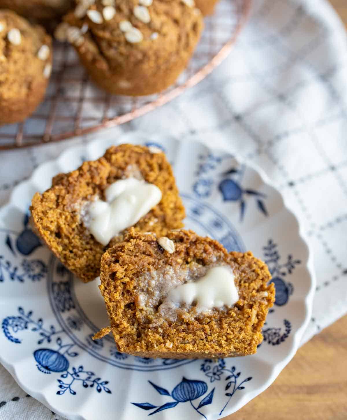 healthy pumpkin muffins baked and on the cooling rack and sliced open with butter inside.