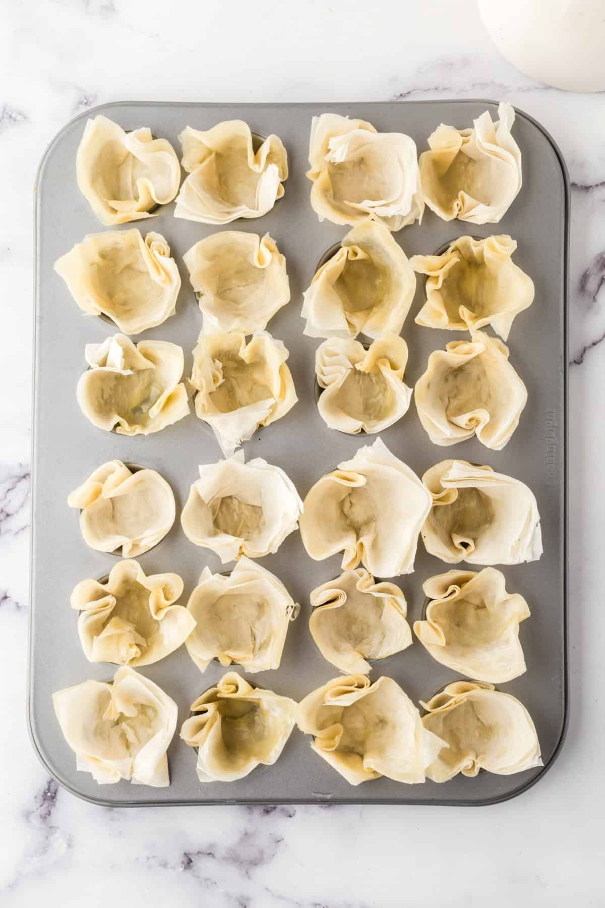 recipe for homemade phyllo cups with unbaked pockets pressed into a muffin tin.