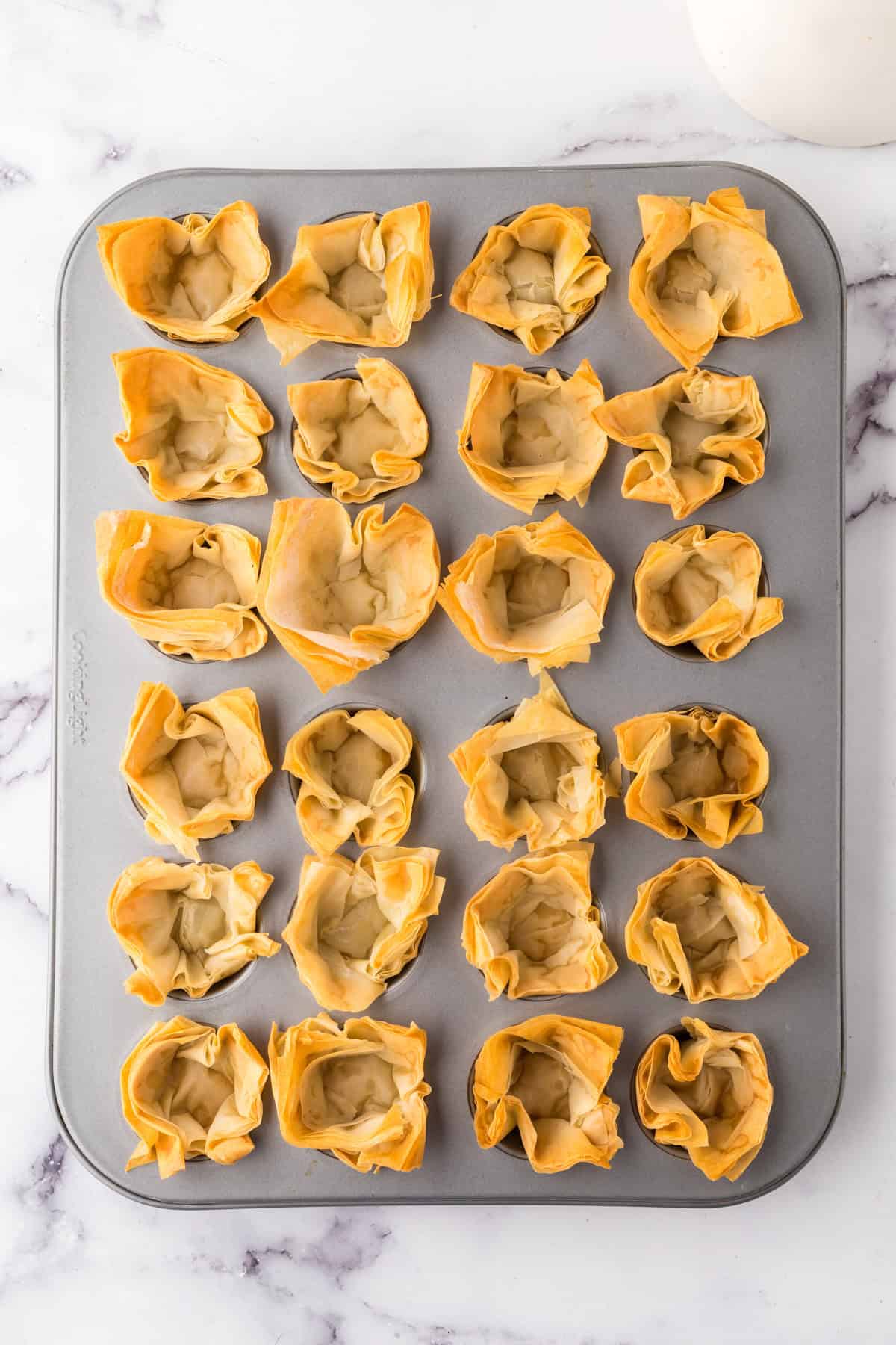 golden and crunchy homemade phyllo cups baked into a muffin tin.