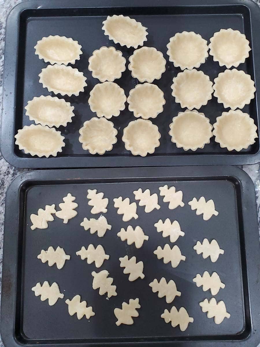 Mini pumpkin pie shells and leaves cut out of pie crust before baking.