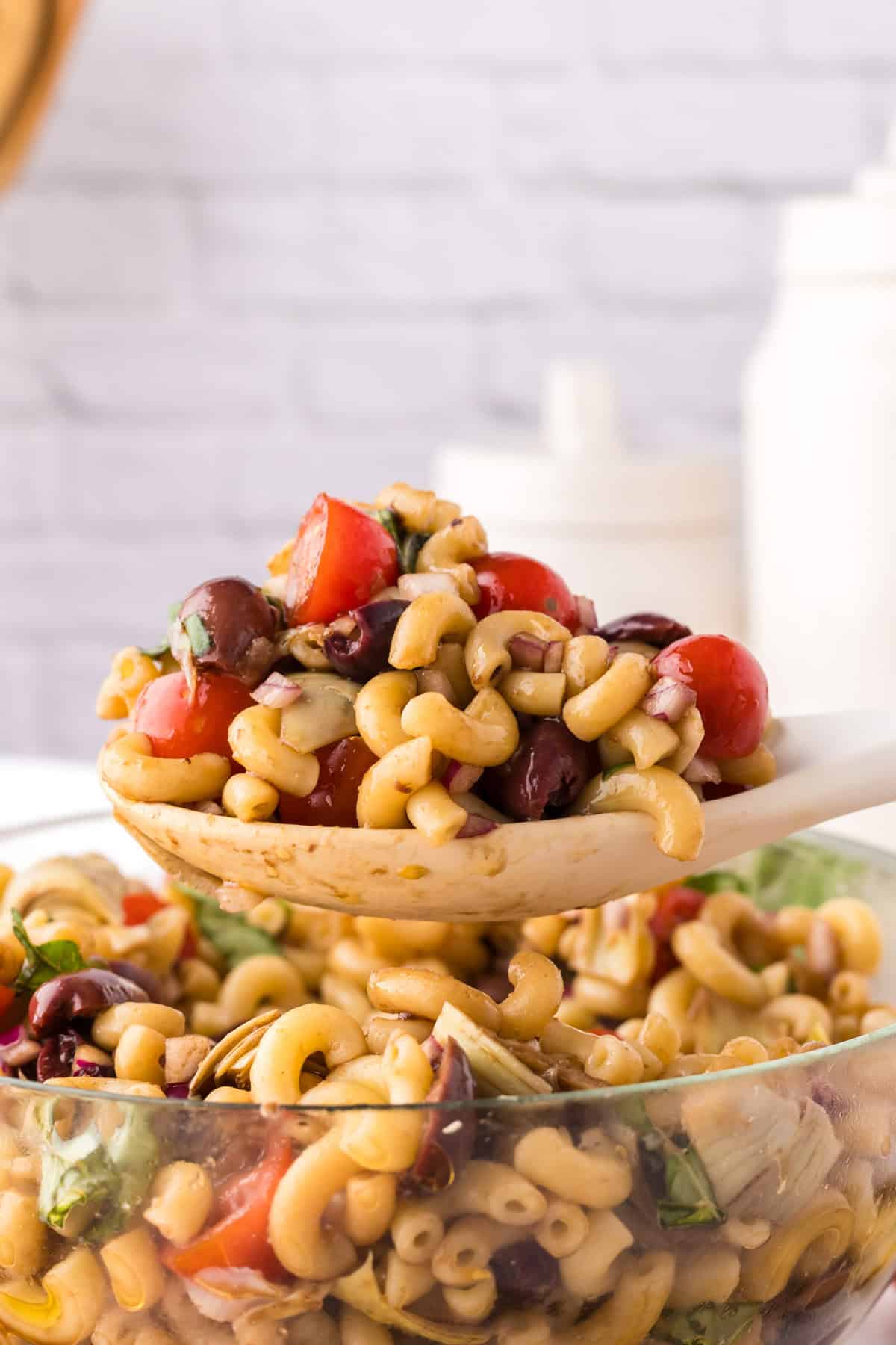 Spoonful of Italian Pasta Salad Recipe over a clear mixing bowl.