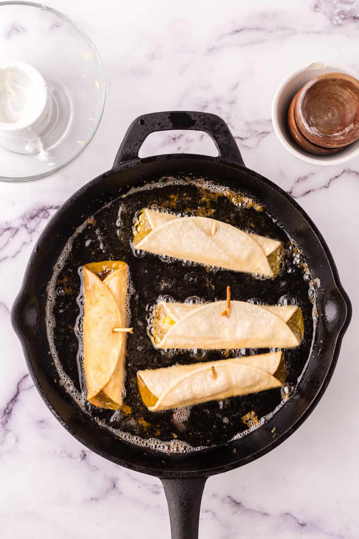 Frying the taquitos in hot oil.