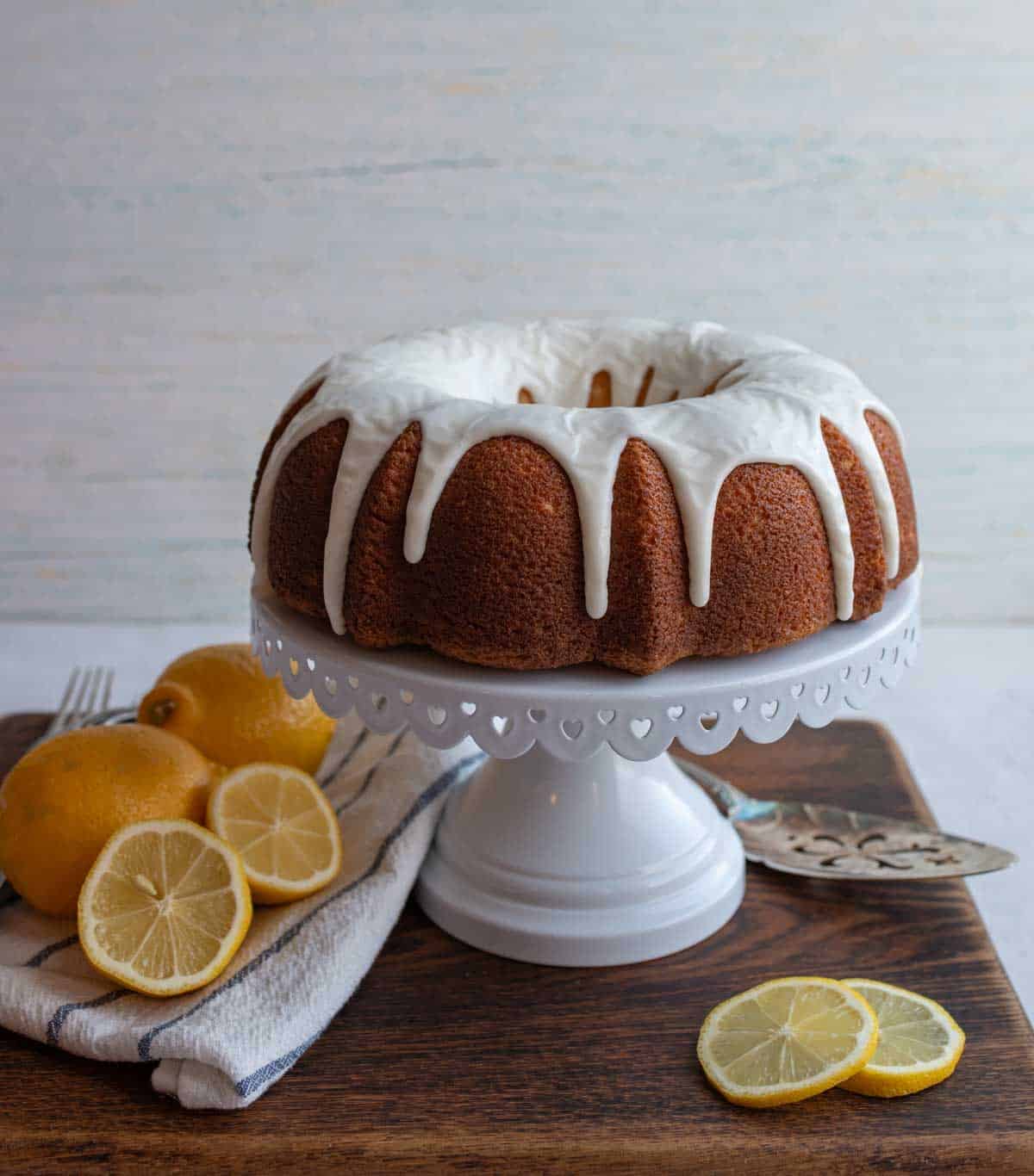 whole round lemon bundt cake with white icing on top on a cake tray.