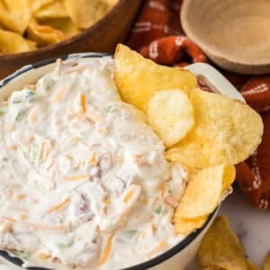 loaded baked potato dip in a bowl with potato chips.