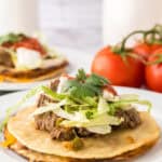 beef piled high with cilantro on top to make Mexican beef tostados.