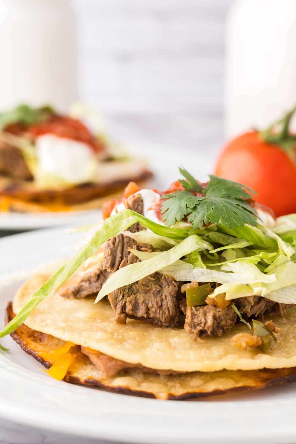 beef piled high with cilantro on top to make Mexican beef tostados.