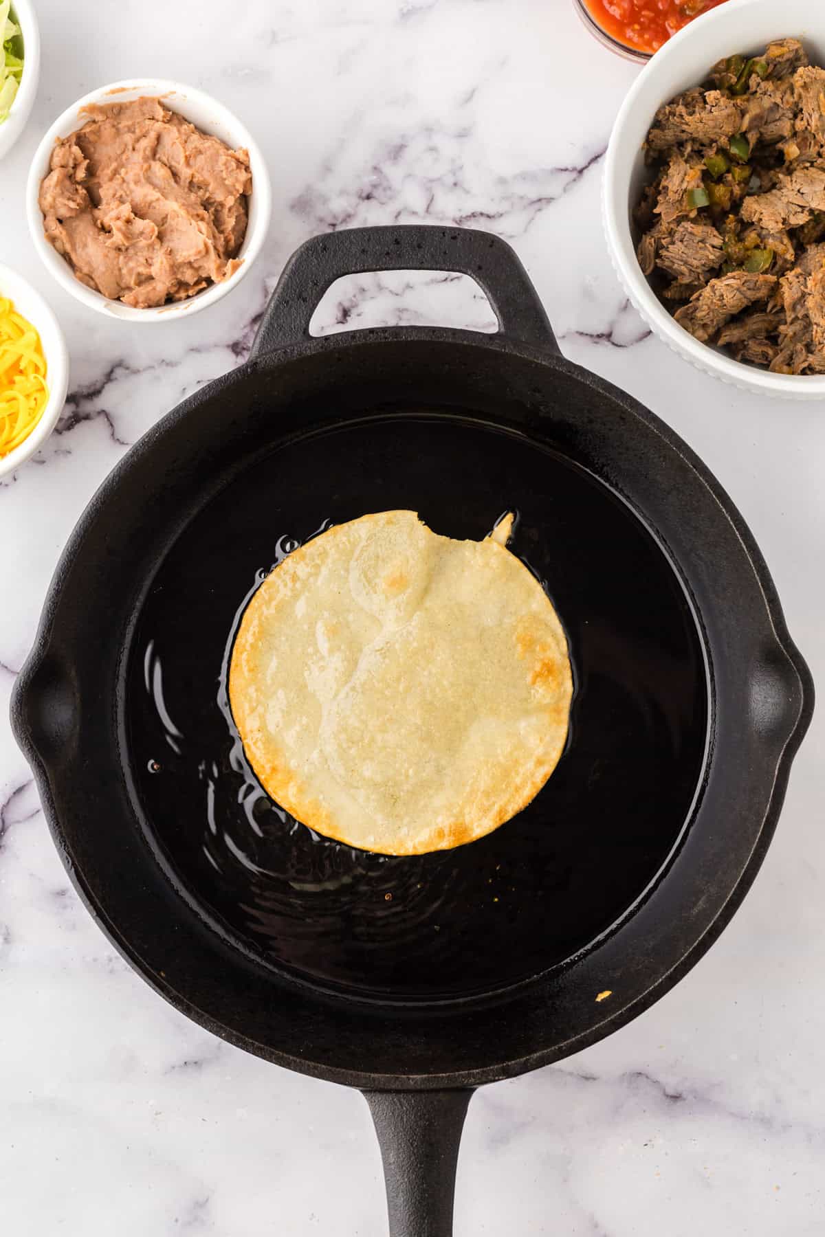 cast iron frying the tortilla for Mexican beef tostados