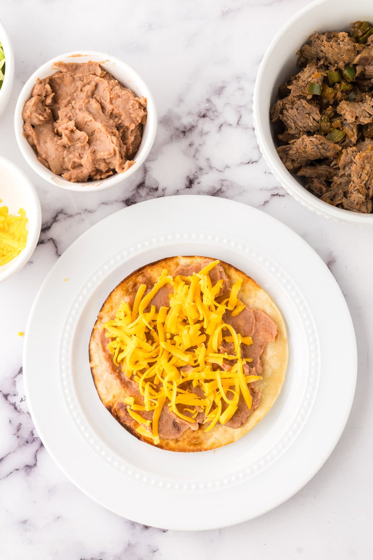 Mexican beef tostado on a round white plate in progress.