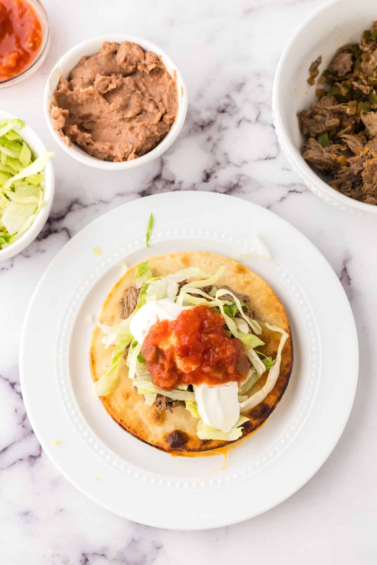 Mexican beef tostado on round white plates.