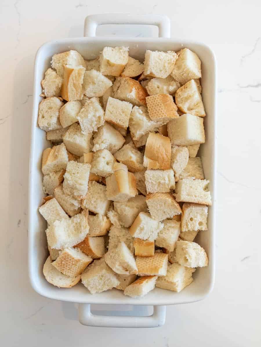 Cubes of French bread in a white baking dish. 