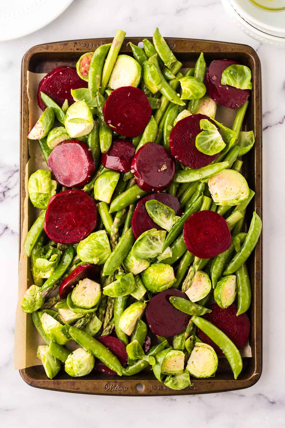 raw spring vegetables on a baking dish before being baked and roasted.