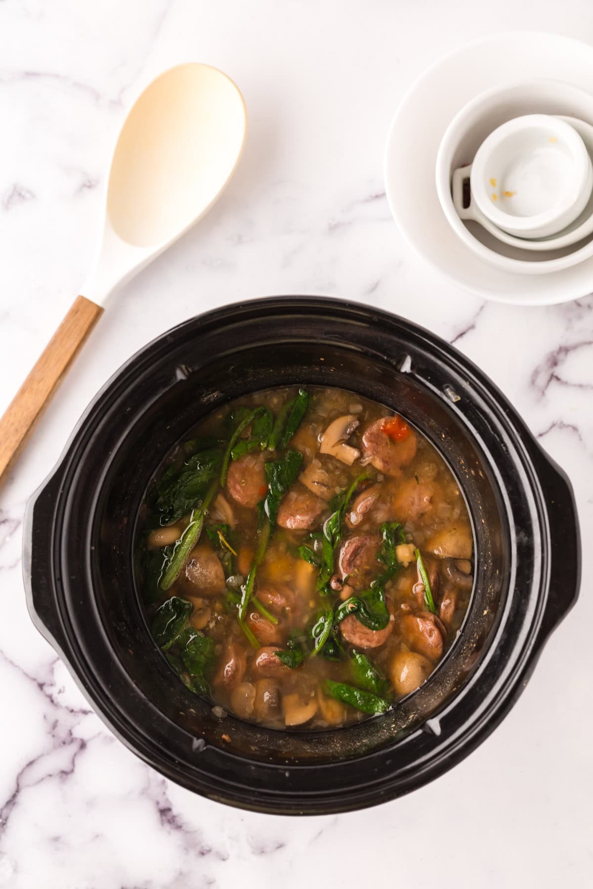 crockpot with sausage bean soup with spinach.
