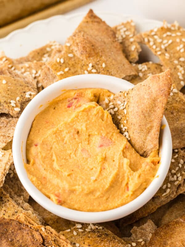 simple lavish bread crackers on a round plate with a bowl of dip in the middle.