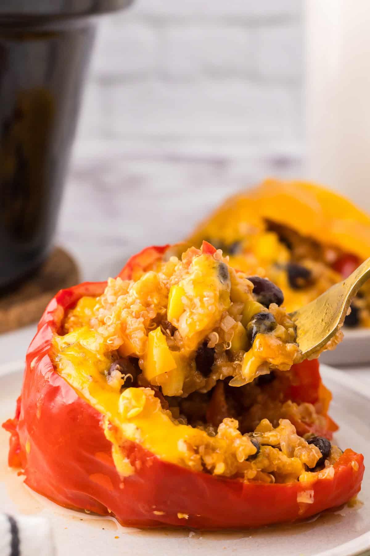 one slow cooked stuffed bell pepper on a round white plate with a fork.