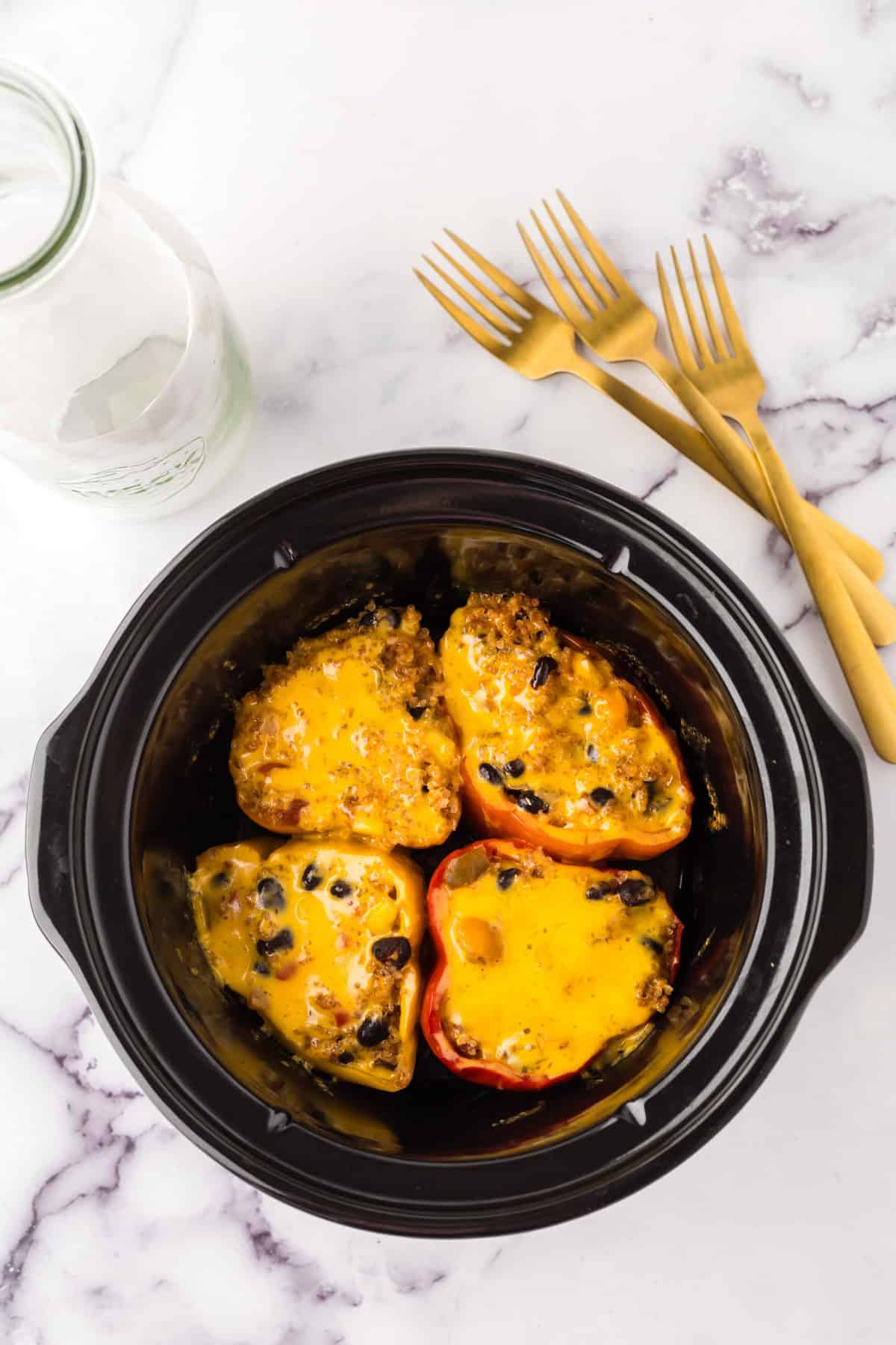 slow cooker bowl with four halved stuffed bell peppers.