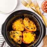 slow cooker bowl with four halved stuffed bell peppers.