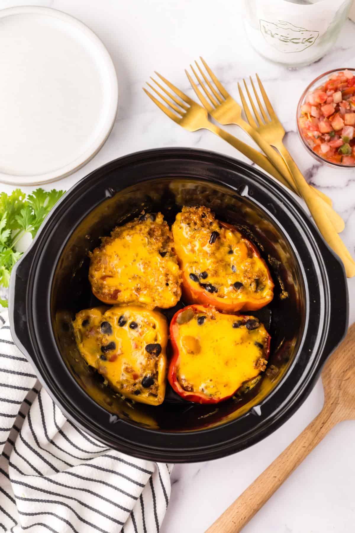 slow cooker bowl with four halved stuffed bell peppers.