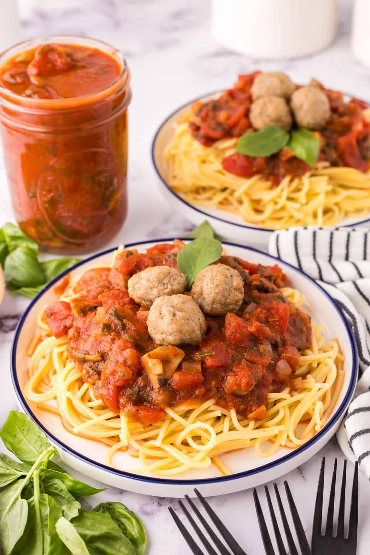 spinach mushroom marinara on a round plate of pasta with meatballs on top.