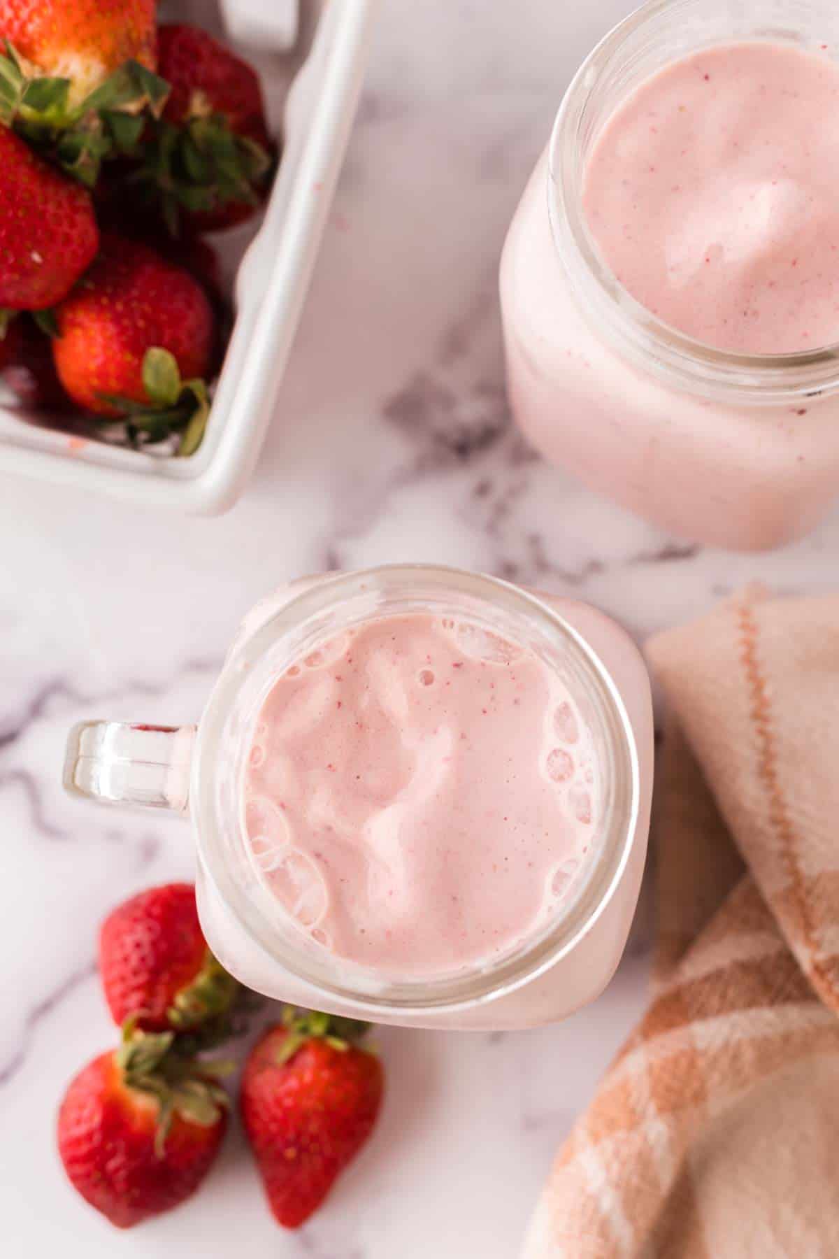 mason jar with a strawberry milkshake inside.