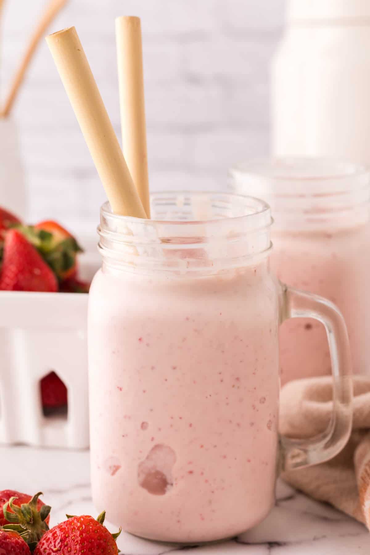 mason jar with a strawberry milkshake inside with bamboo straws.